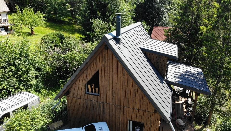 Plechová falcovaná střecha chaty v lese
